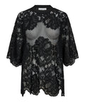 Den sorte Curvey Lace Hem Tee fra Haute L'amitié er en elegant og moderne bluse, der kombinerer feminin finesse med et strejf af kant. Blusen er fremstillet i 100 % polyester, hvilket giver den en let og behagelig kvalitet, perfekt til både hverdag og festlige lejligheder.
